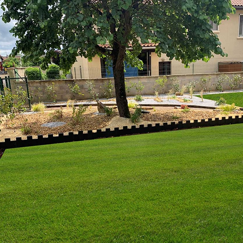 Jardin sec avec olivier, statue et gravier coloré Aménagement paysager méditerranéen avec statue blanche, gravier ocre et gris, olivier, et gazon synthétique près d'un mur beige.