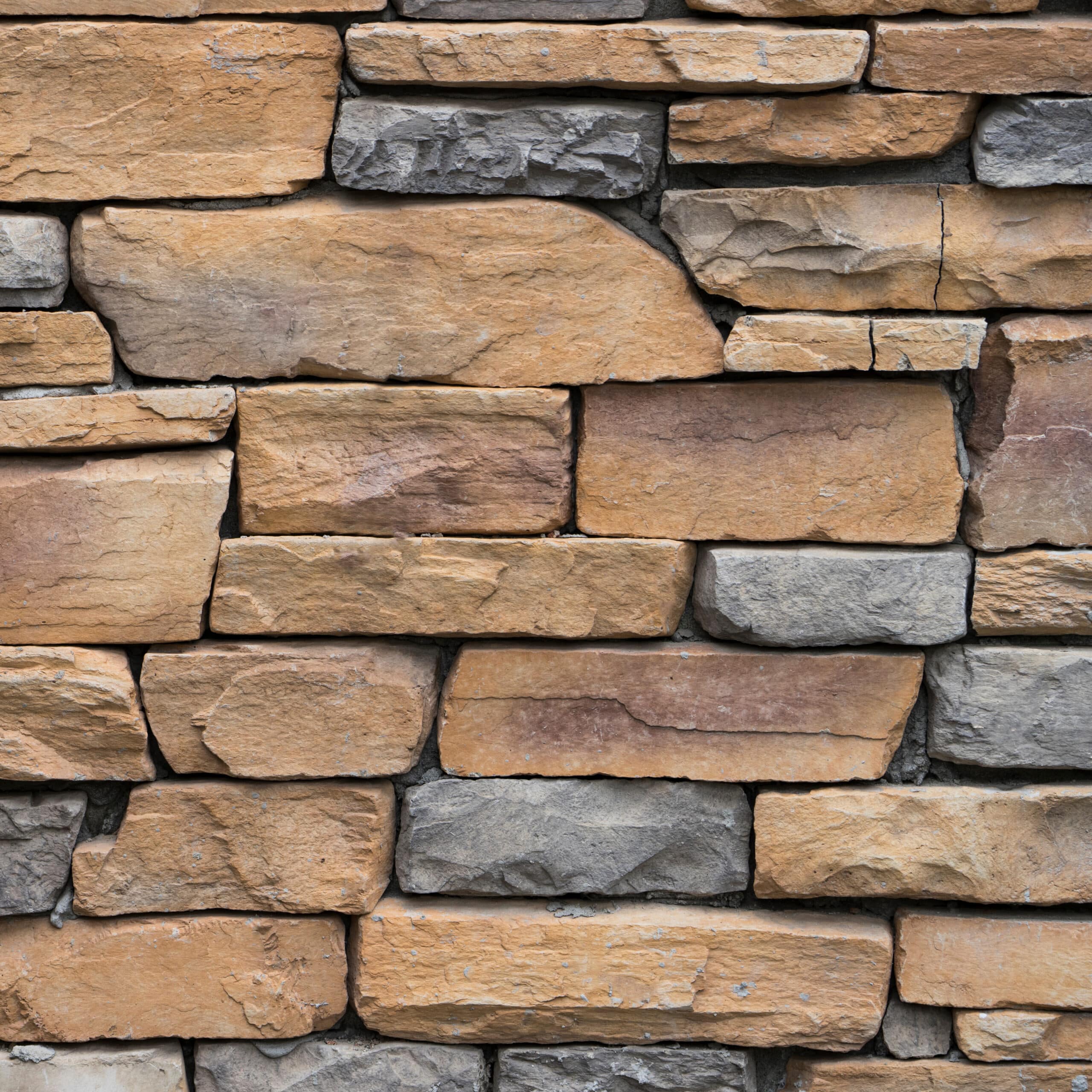 Jardin sec avec olivier, statue et gravier coloré Aménagement paysager méditerranéen avec statue blanche, gravier ocre et gris, olivier, et gazon synthétique près d'un mur beige.